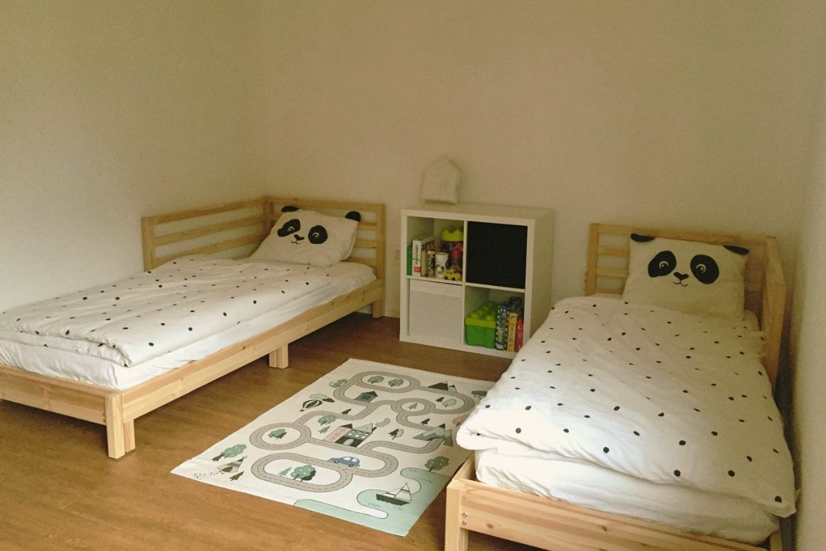 Detská izba s dvomi posteľami z borovice, panda vankúšmi a hracím kobercom s cestičkami