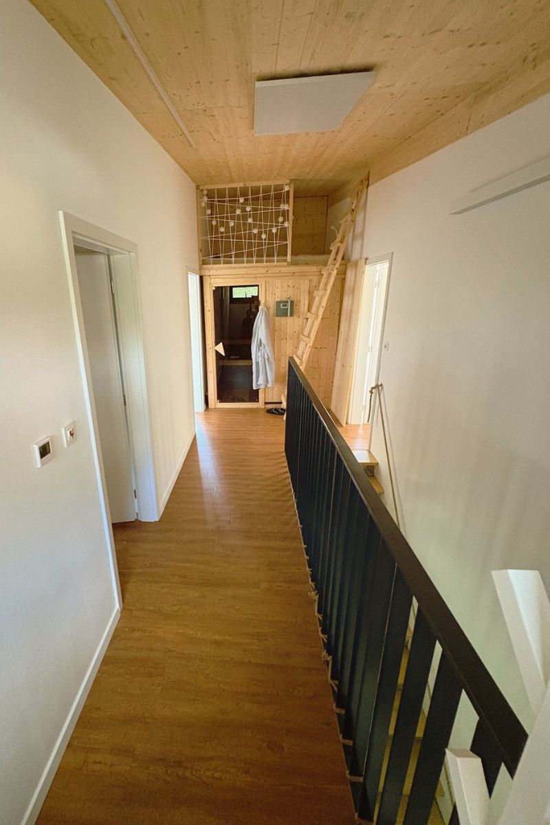 Chodba na poschodí s drevom obloženým vstupom do sauny a rebríkom na bunker